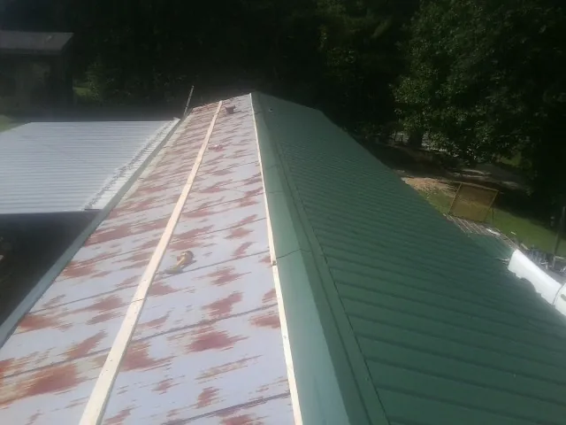 Old rusted panels beside newly installed green metal roofing — Wind Damage Roof Repair by Roofing Brothers in Flag Pond