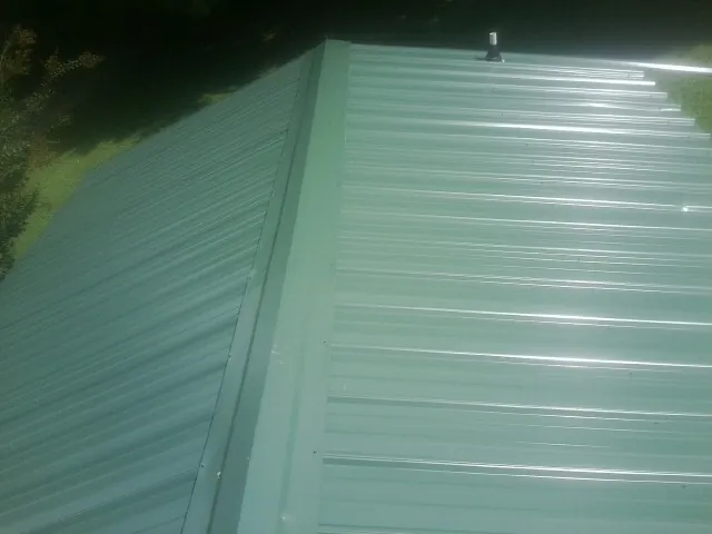 New green metal panels meeting at the ridge of a roof — Flat Roof Repair work by our crew in Flag Pond