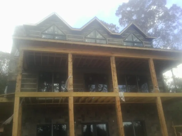 Dormers and porch framing on a large log home under construction — Roof Coating work by our crew in Flag Pond
