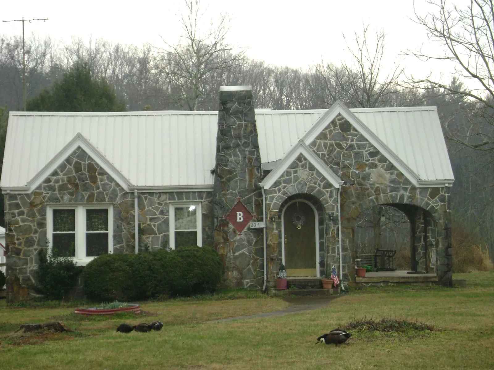 White metal roof on a stone cottage with steep gables in Flag Pond