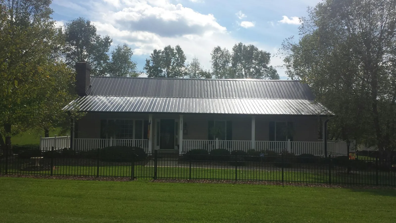 Gray metal roof on a brick ranch with a full width front porch — Gutter Guard Installation work by our crew in Flag Pond