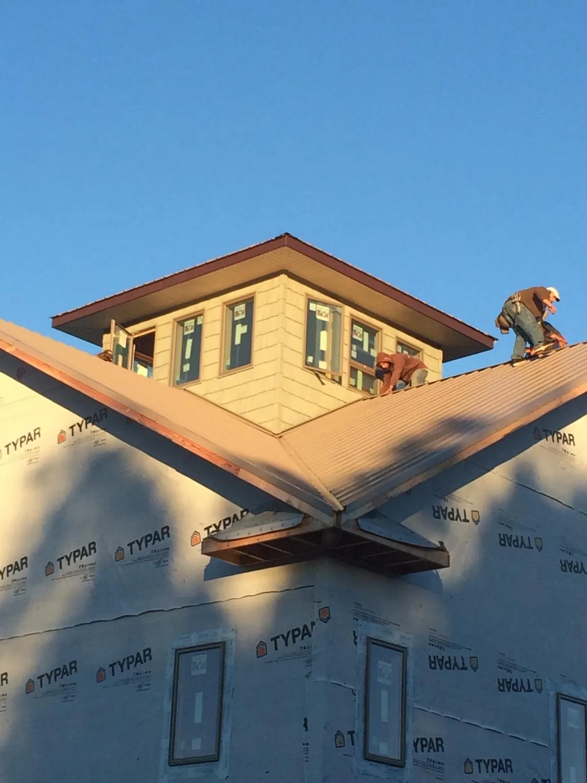 Roofers working around a rooftop cupola on a new metal roof at sunset — Roof Waterproofing in Flag Pond by Roofing Brothers